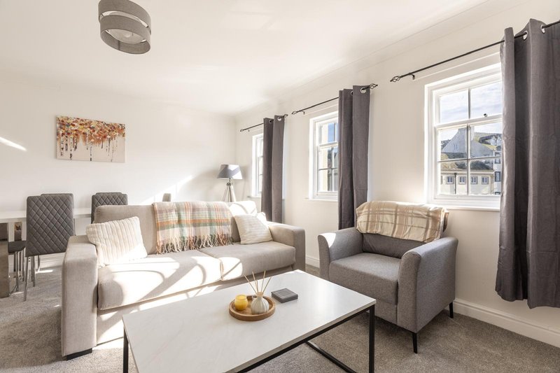 Bright living room with grey sofa, armchair, white coffee table and large windows