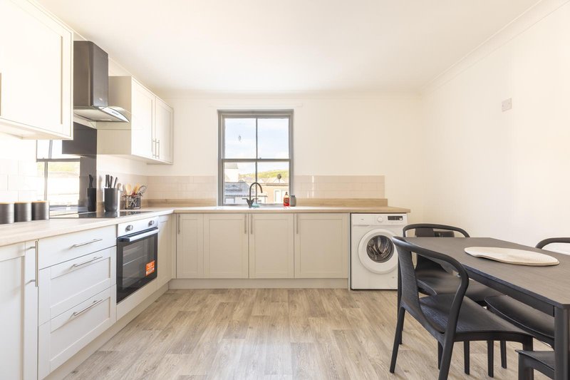 Modern kitchen with white cabinets, built-in appliances, dining table and chairs