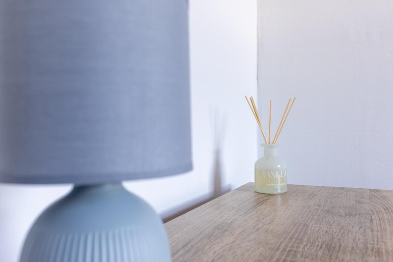 Wooden table with reed diffuser and blue table lamp in soft focus