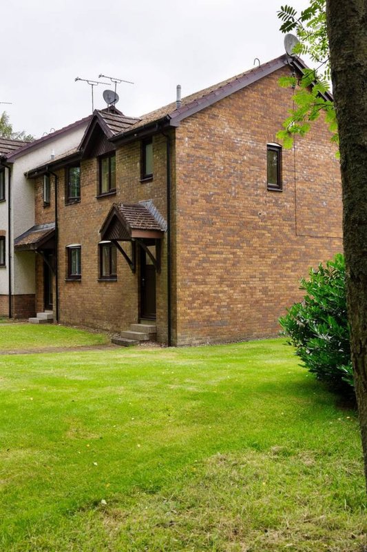 Brick house exterior with lawn, garden, entrance door and windows