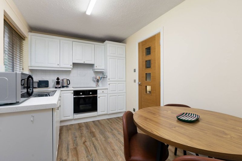 Kitchen and dining area with white cabinets, wooden table, and modern appliances