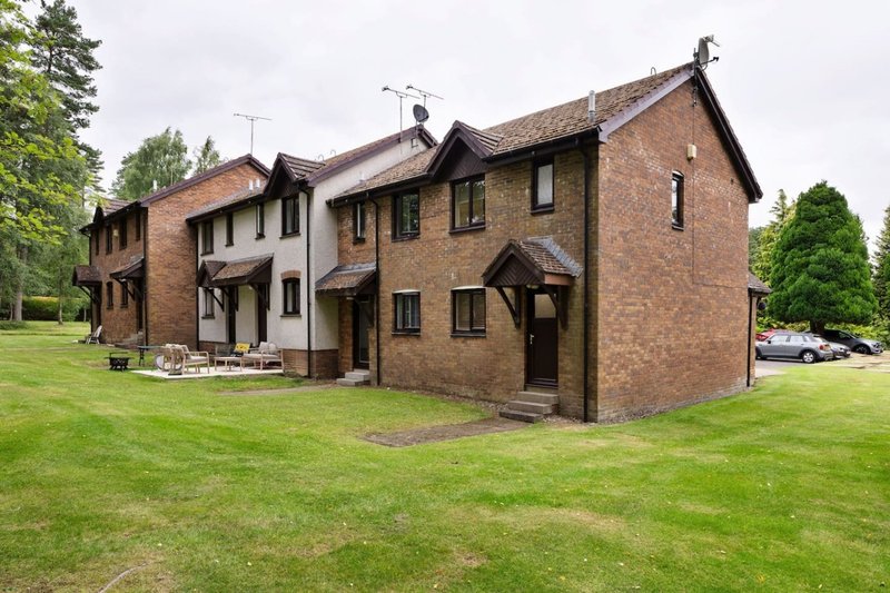 Brick residential property exterior with manicured lawn, multiple entrance doors and windows