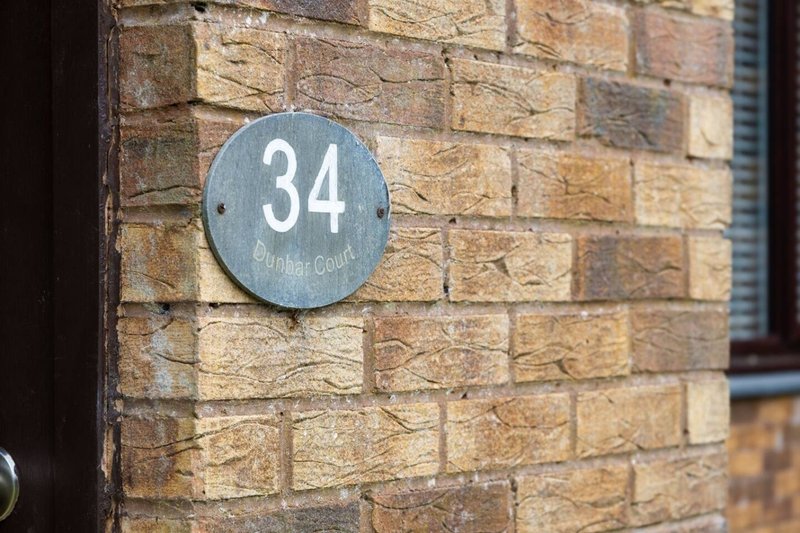 Brick exterior wall with circular blue house number 34 plaque