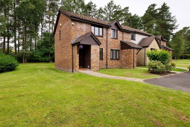 Brick two-storey detached house with driveway, manicured lawn and mature trees