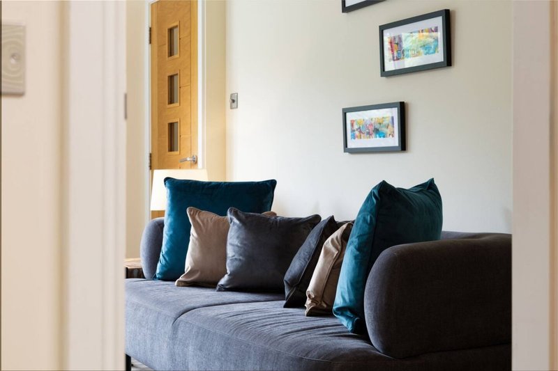 Modern living room with dark sofa, blue and brown cushions, framed artwork on walls