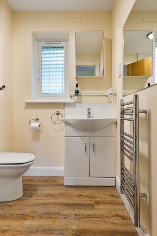 Modern bathroom with white sink vanity, toilet, heated towel rail and mirror