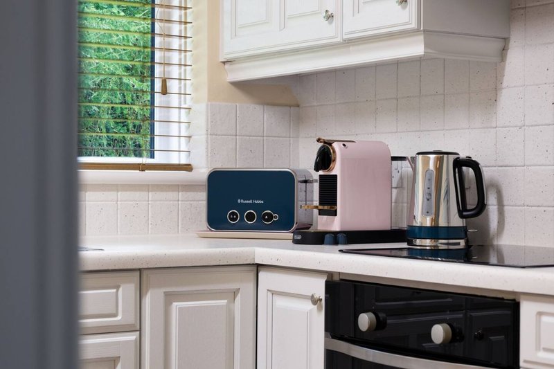 Kitchen countertop with white cabinetry, small appliances, and window overlooking garden