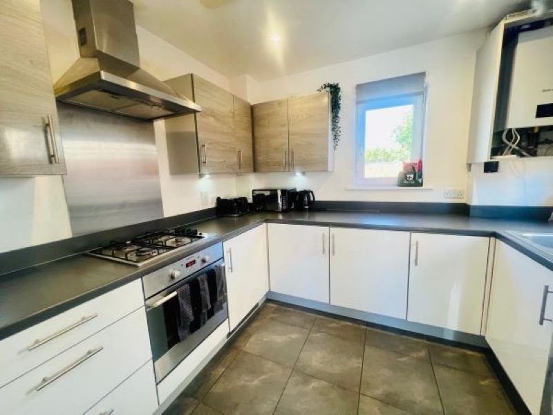 Modern kitchen with white cabinetry, black countertops, stainless steel appliances and window