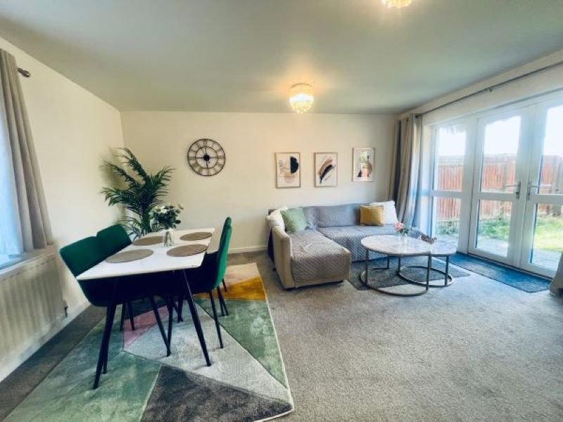 Modern open-plan living room with dining table, grey sofa, coffee table and large windows