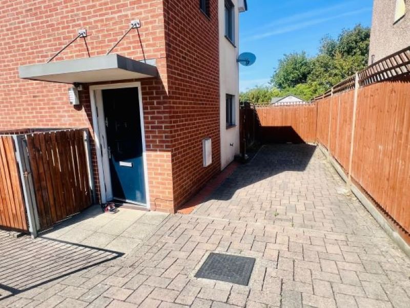 Brick property exterior with paved driveway, wooden fencing, and blue entrance door
