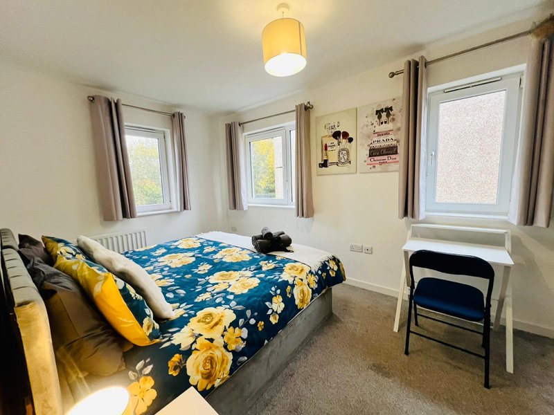 Bright bedroom with double bed, yellow floral bedding, multiple windows and ceiling light