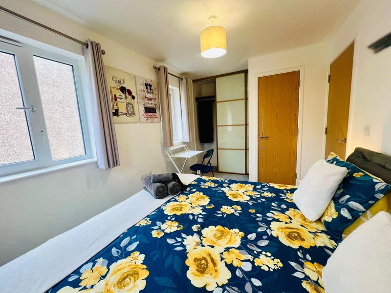 Bedroom with double bed, floral duvet, wooden doors, window and ceiling light