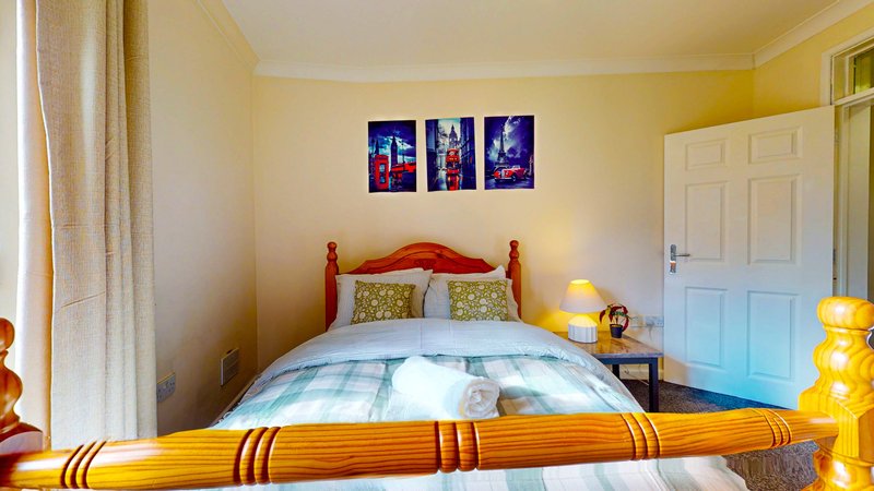 Bright bedroom with red wooden bed, checkered bedding, yellow walls and framed artwork