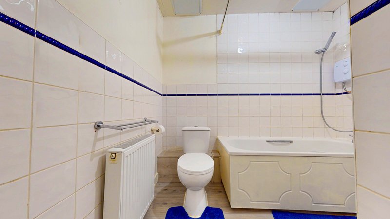Bathroom with toilet, bathtub, radiator, and blue tile accents
