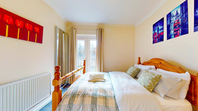 Bright bedroom with double bed, wooden headboard, white bedding, and decorative wall art