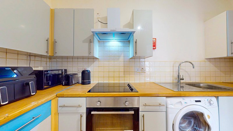 Kitchen with yellow countertop, white cabinetry, integrated appliances and washing machine