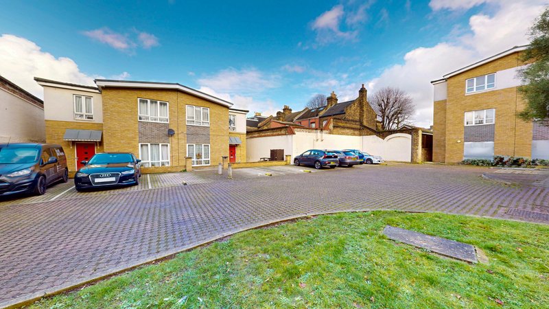 Modern residential complex with brick houses, paved driveway, parked cars and green lawn