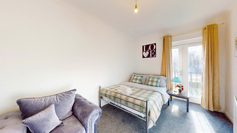 Bright bedroom with single bed, seating area, yellow curtains and balcony access