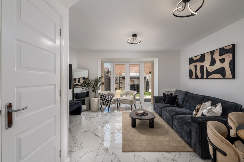 Open-plan living room with black sofa, dining area, and glass doors to garden