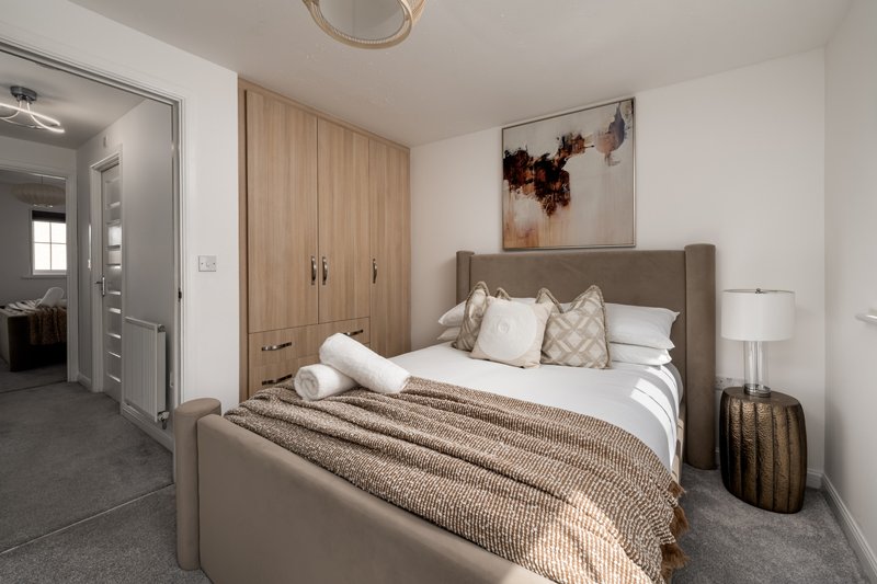 Modern bedroom with upholstered bed, wooden wardrobe, neutral bedding and wall art