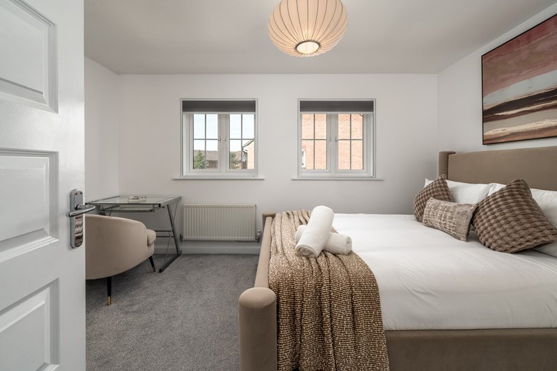 Bright bedroom with double bed, desk, chair, two windows and ceiling lamp