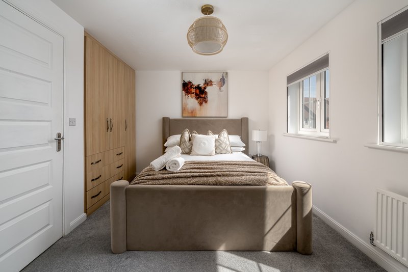 Modern bedroom with double bed, wooden wardrobe, pendant light and white walls