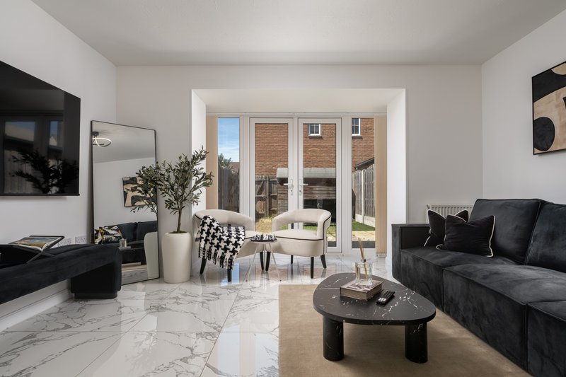 Modern living room with black sofa, marble floor, glass doors opening to garden