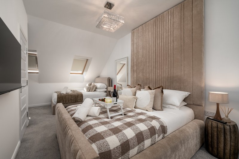 Bright attic bedroom with twin beds, patterned bedding, cushions and wooden headboard