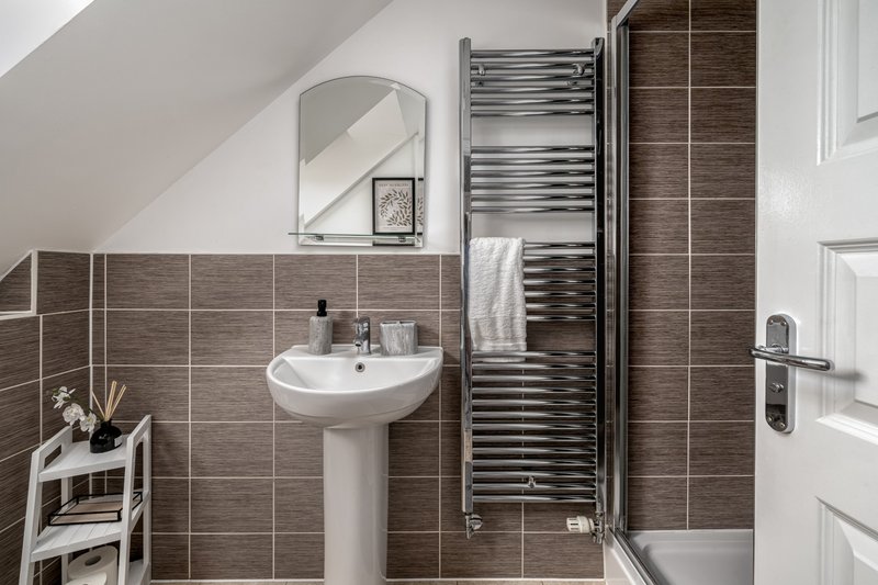 Modern bathroom with pedestal sink, mirror, heated towel rail and shower enclosure