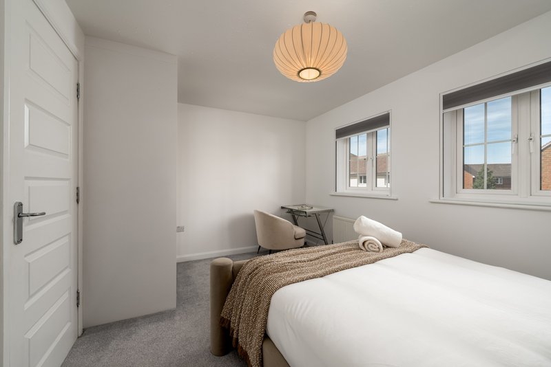 Bright bedroom with double bed, pendant light, windows with views, and grey carpet flooring