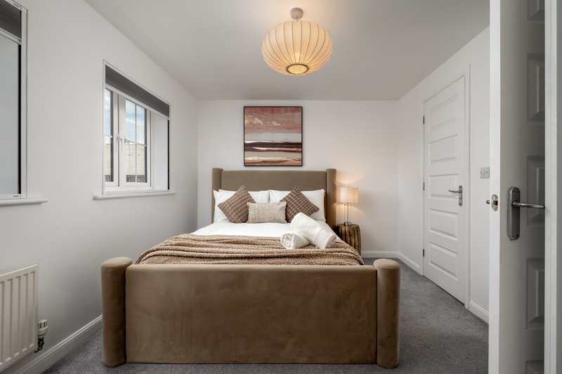 Modern bedroom with brown upholstered bed, white bedding, pendant light fixture and window
