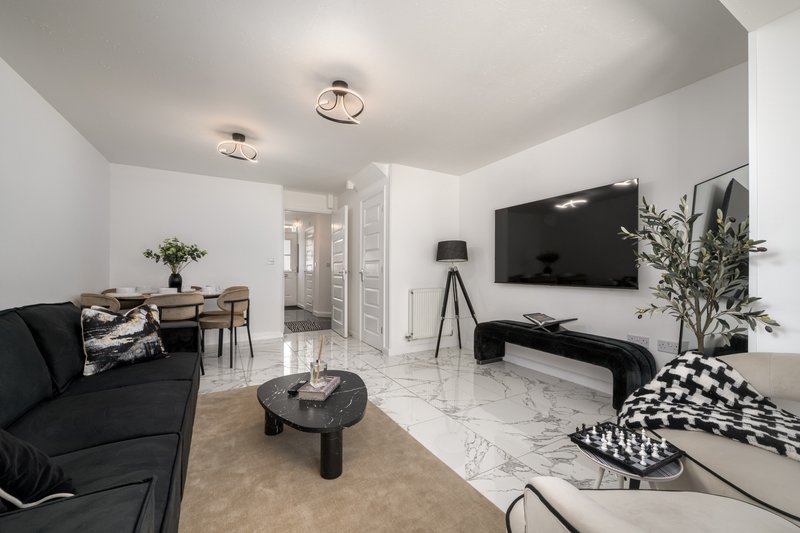 Modern living room with black sofa, marble coffee table, wall-mounted TV and potted plants