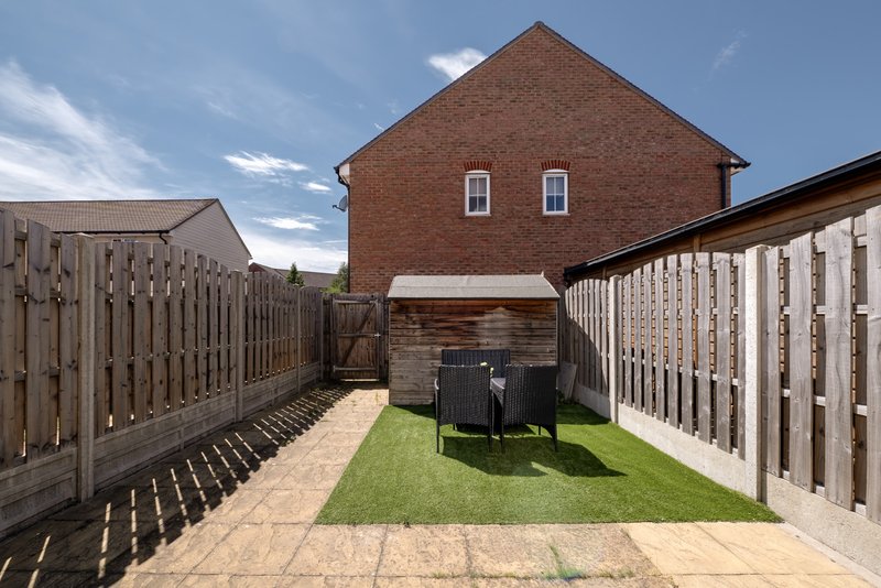 Brick house with enclosed garden, paved patio, grass area and wooden fencing