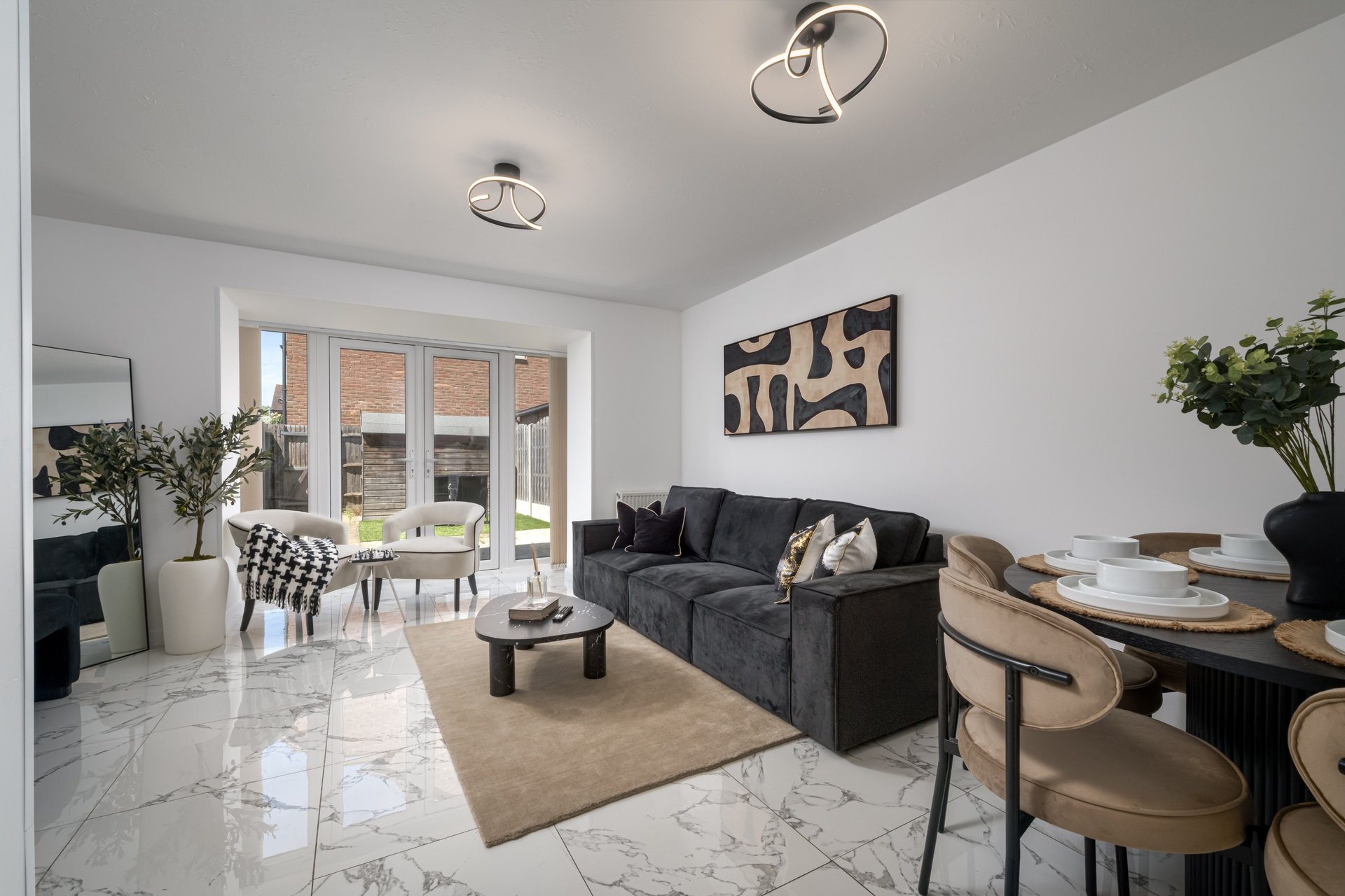 Open-plan living and dining room with grey sofa, dining table, marble flooring and patio doors