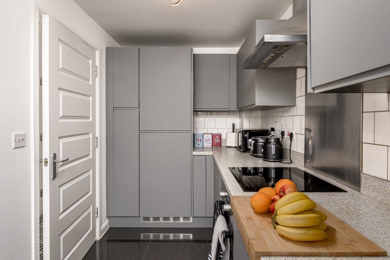 Modern galley kitchen with grey cabinetry, stainless steel appliances and fresh fruit on counter