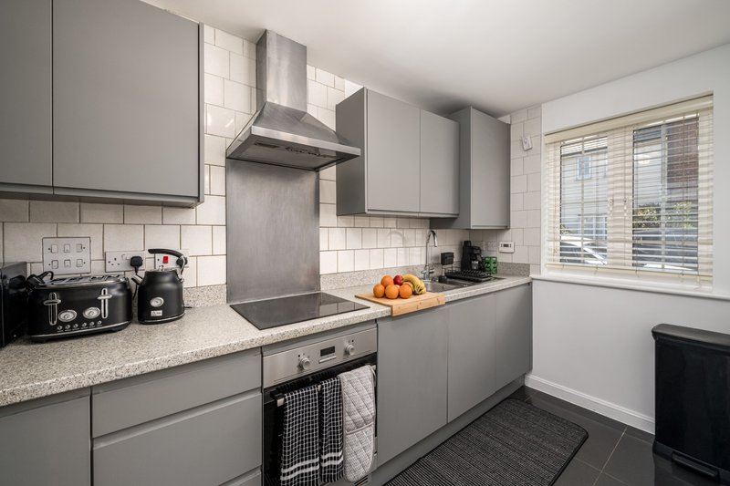 Modern kitchen with gray cabinets, stainless steel appliances, white subway tiles, and granite countertop