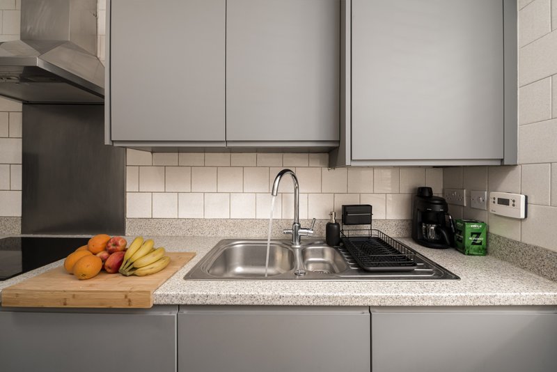 Modern kitchen with gray cabinetry, stainless steel sink, subway tile backsplash and countertop produce