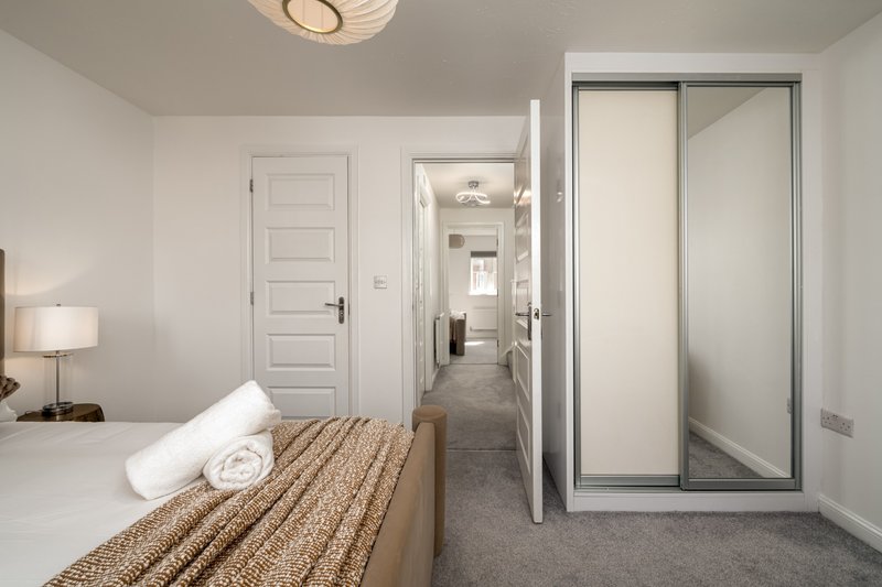 Modern bedroom with double bed, wardrobe, and door to ensuite bathroom