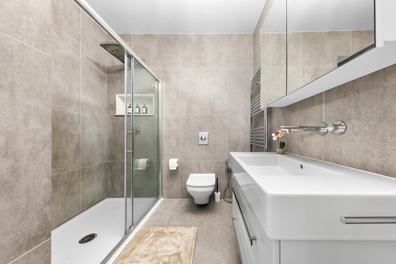 Modern bathroom with walk-in shower, white sink, toilet and heated towel rail