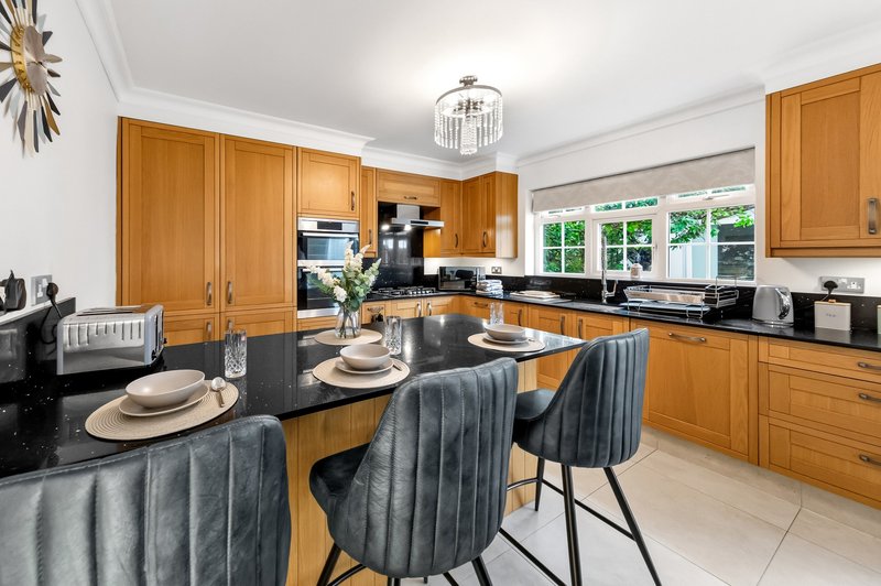 Modern kitchen with wooden cabinets, black countertops, island seating, and large windows