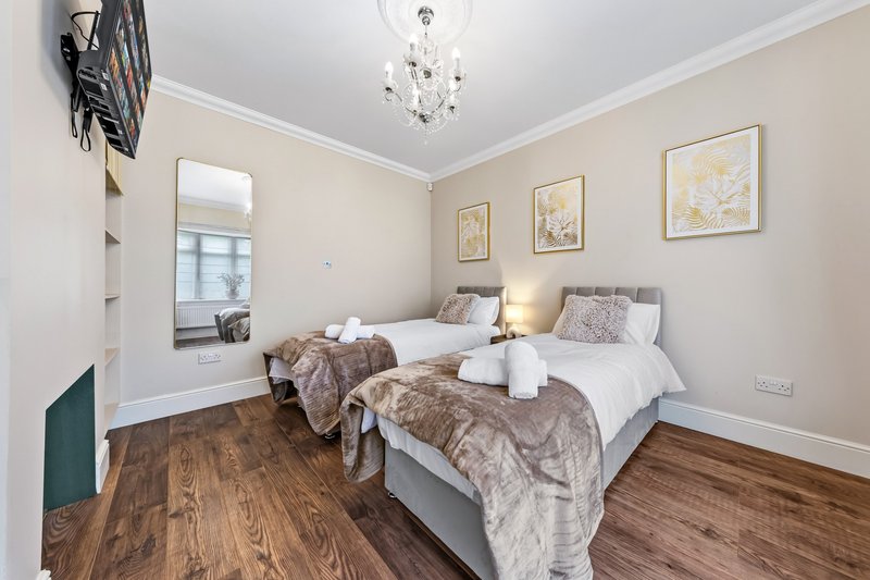 Twin bedroom with two single beds, wooden floor, mirror and framed wall art