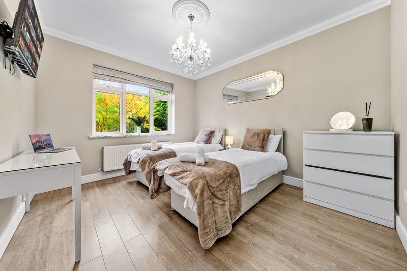 Bright bedroom with double bed, white furniture, wooden flooring and garden view