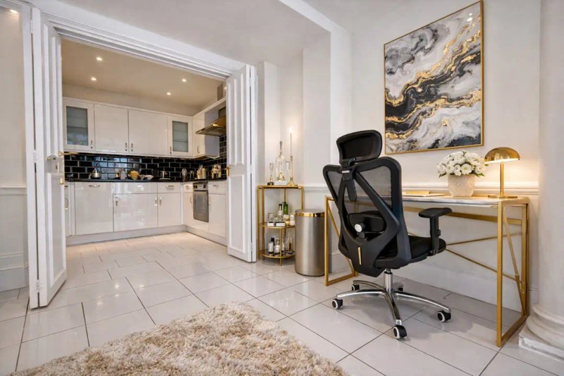 Open-plan living space with modern kitchen, office desk, black chair and marble artwork