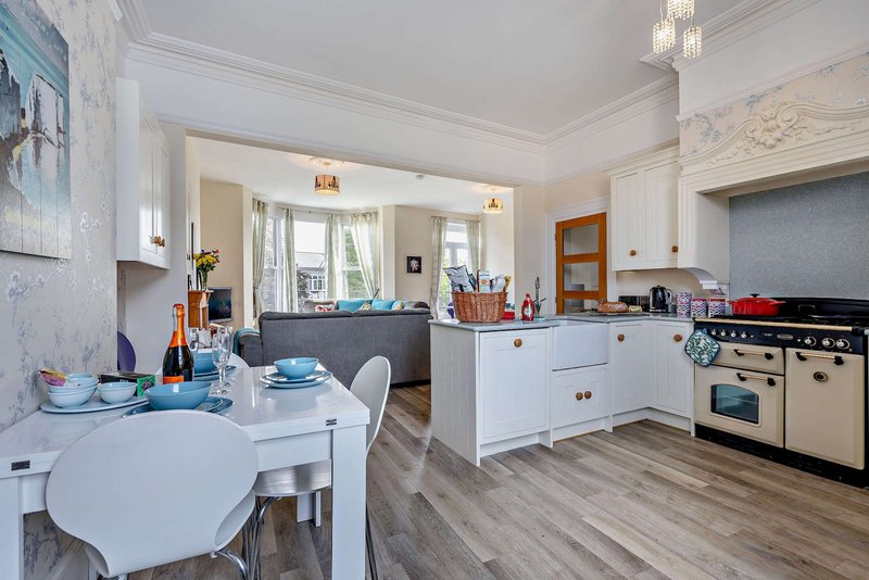 Open-plan kitchen and dining area with white cabinetry, cream range cooker, and circular dining table