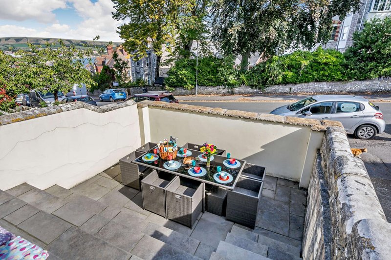 Outdoor rooftop terrace with dining table, cream awning, mountain views and parked cars