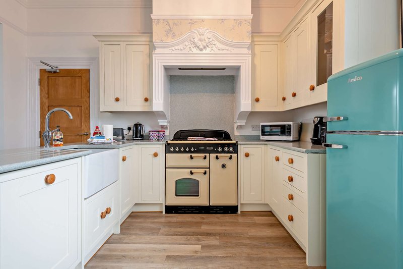 Modern kitchen with cream cabinets, turquoise fridge, cream range cooker and wooden flooring