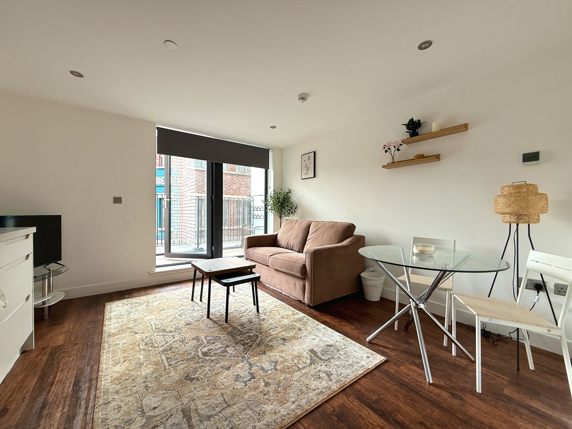 Modern open-plan living room with sofa, dining table, wooden floors and large windows