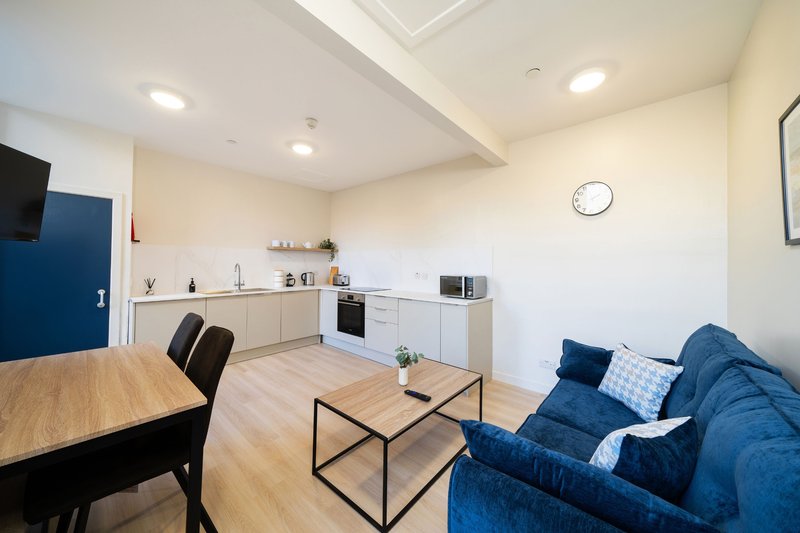 Open-plan studio with kitchen, dining table, and blue sofa seating area