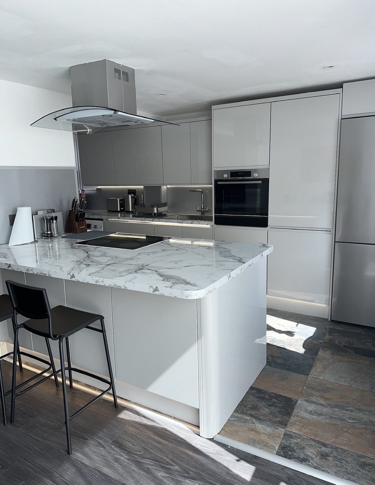 Modern white kitchen with marble island, built-in appliances, and bar seating