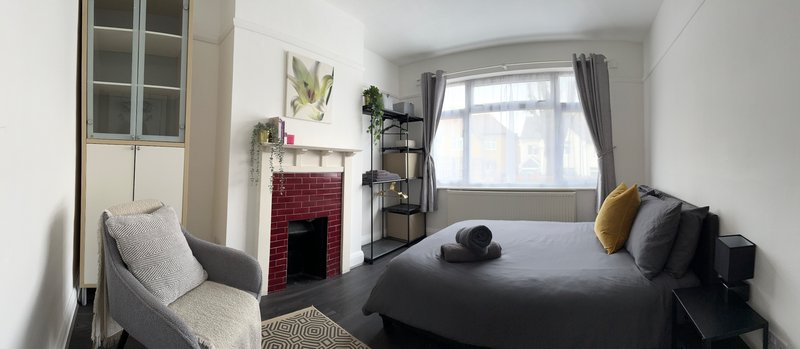 Bedroom with double bed, fireplace, window with curtains, and storage furniture